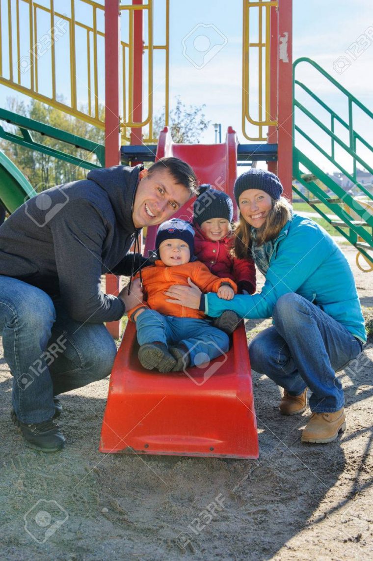 Heureuse Souriante Jeune Famille De Quatre Personnes À L'aire De Jeux Pour  Enfants Dans Le Parc serapportantà Jeux Pour Jeunes Enfants