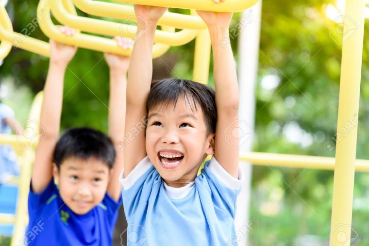 Jeune Garçon Asiatique Accrocher La Barre Jaune De Sa Main Pour Exercer Au  Terrain De Jeu De La Porte Sous Le Grand Arbre. intérieur Jeux De Grand Garçon