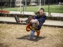 Jeune Homme Revivant Son Enfance Dans Une Aire De Jeux Pour Enfants À  Cheval Sur Un Siège De Printemps Rouge Coloré Avec Un Sourire Heureux Dans  Un avec Jeux Pour Jeunes Enfants