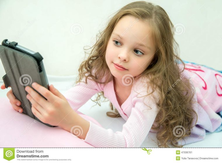 Petite Fille Heureuse Se Trouvant Sur Le Lit Avec La avec Tablette Enfant Fille