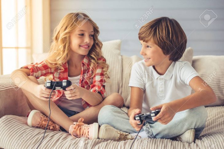 Jolie Petite Fille Et Garçon Jouent Console De Jeu, Se Regardant Et  Souriant Tout En Étant Assis Sur Le Canapé À La Maison serapportantà Tout Les Jeux De Fille Et De Garcon